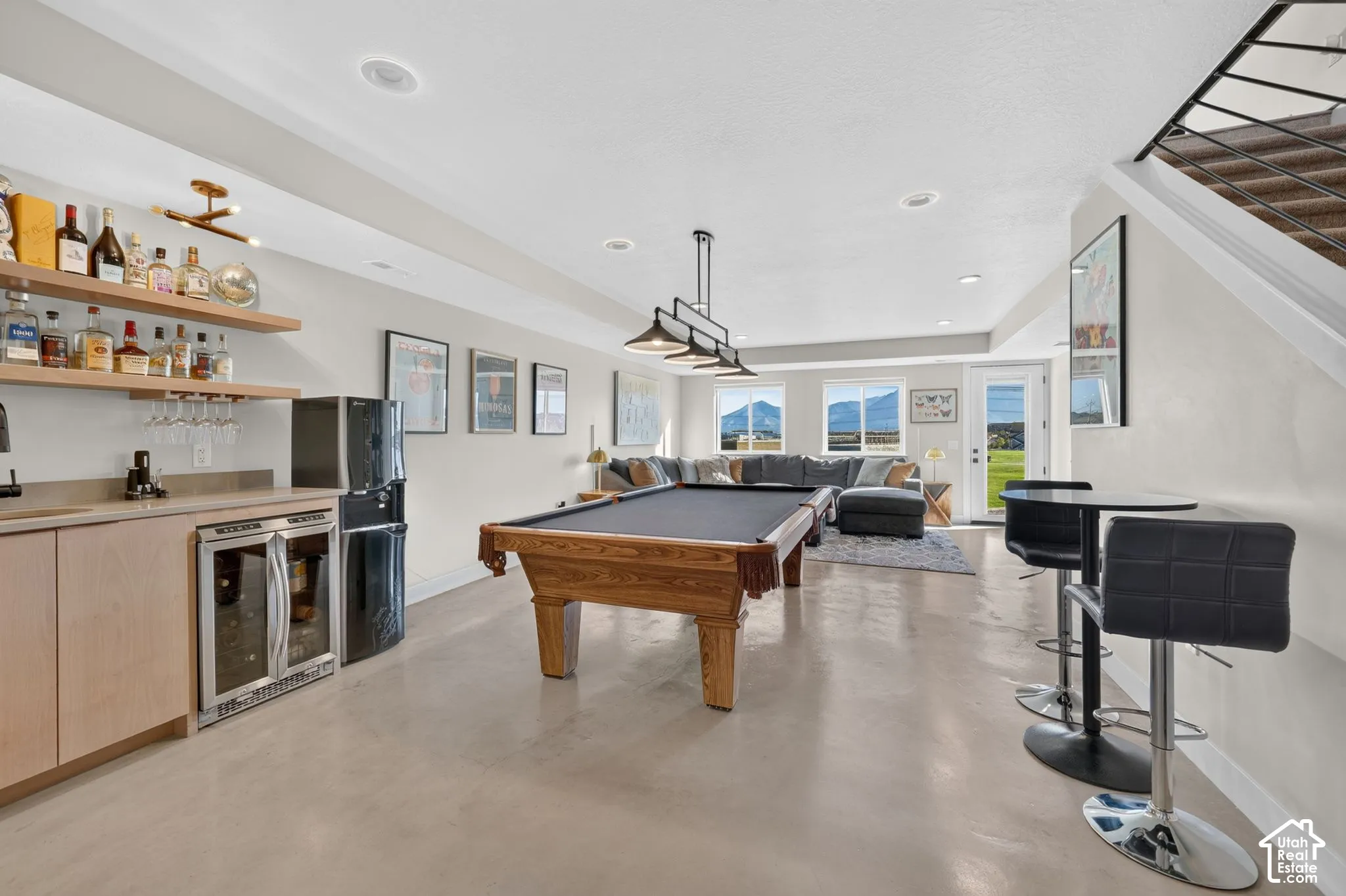 Recreation room featuring a built-in wet bar with wood cabinetry, integrated beverage refrigerators, and open shelving