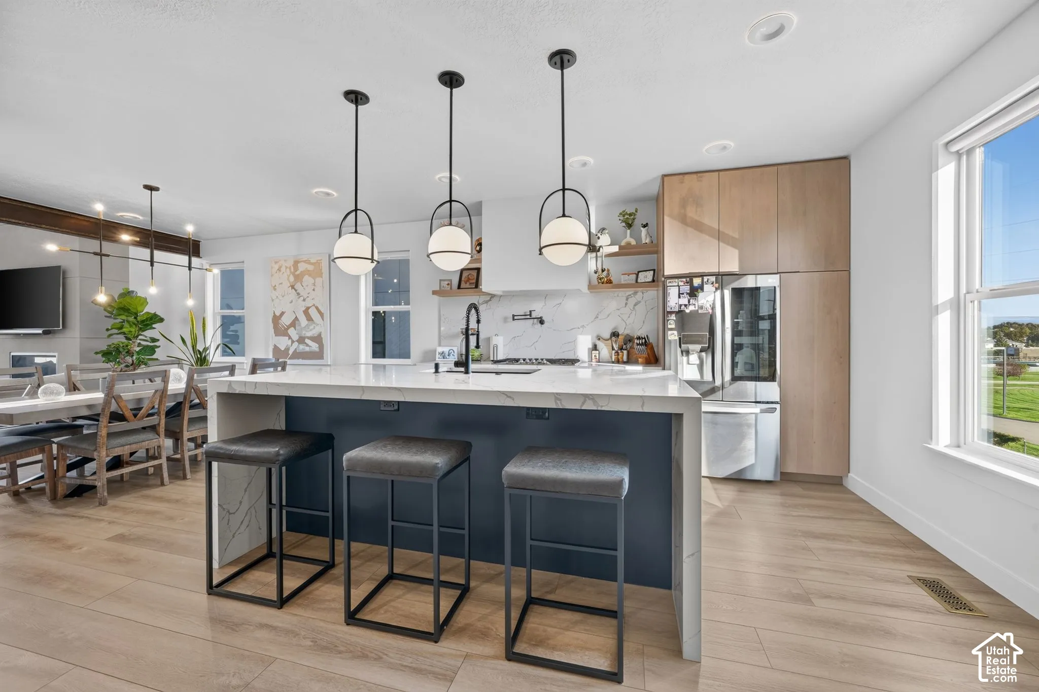 Kitchen island with a light-toned countertop and dark blue base, complemented by three contemporary pendant lights