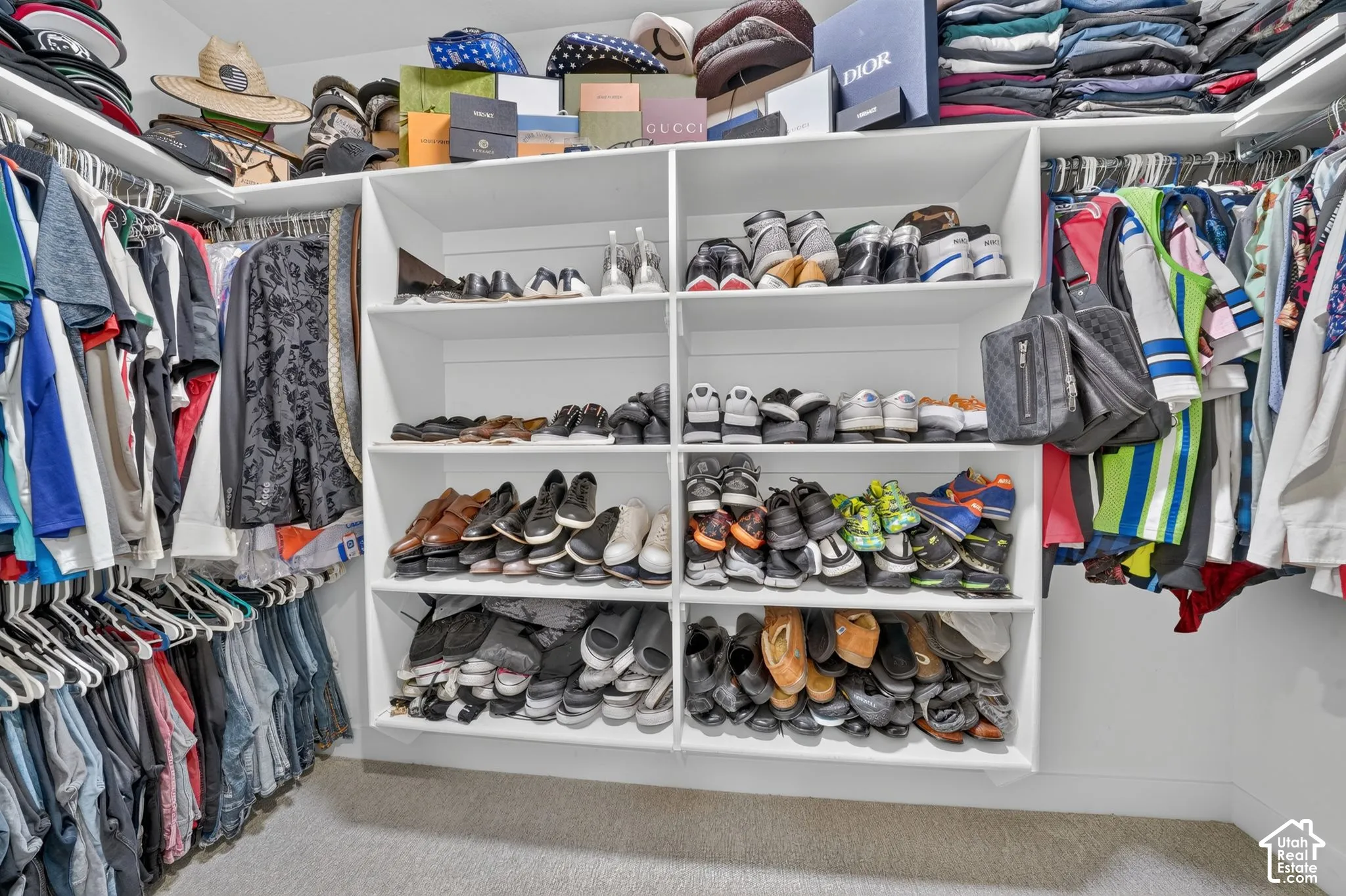 White built-in shelving, integrated shoe storage, multiple hanging rods, and light-toned carpet