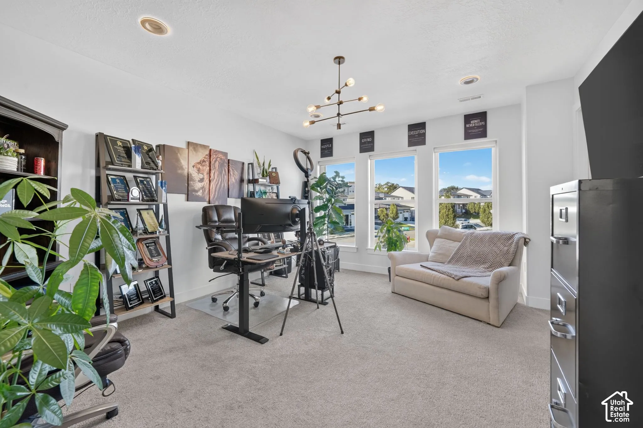 Carpeted room with recessed lighting, a contemporary chandelier, and three large windows