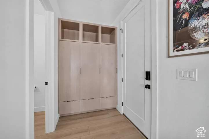Wood-finish flooring with full-height built-in cabinetry featuring open shelving and drawer storage