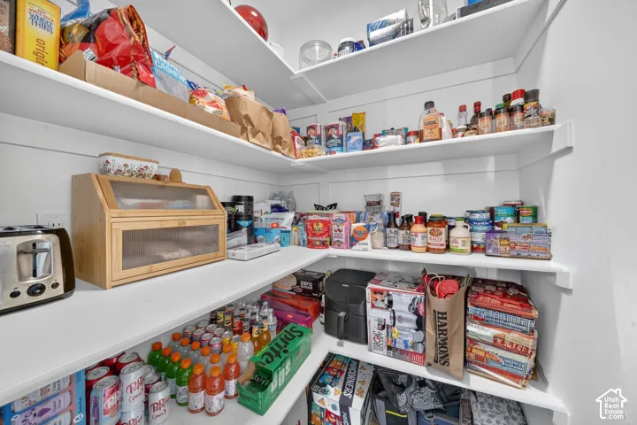 Spacious pantry featuring multiple curved shelving units with ample storage capacity, built-in wooden bread box with glass front, and organized display of canned goods and dry goods throughout