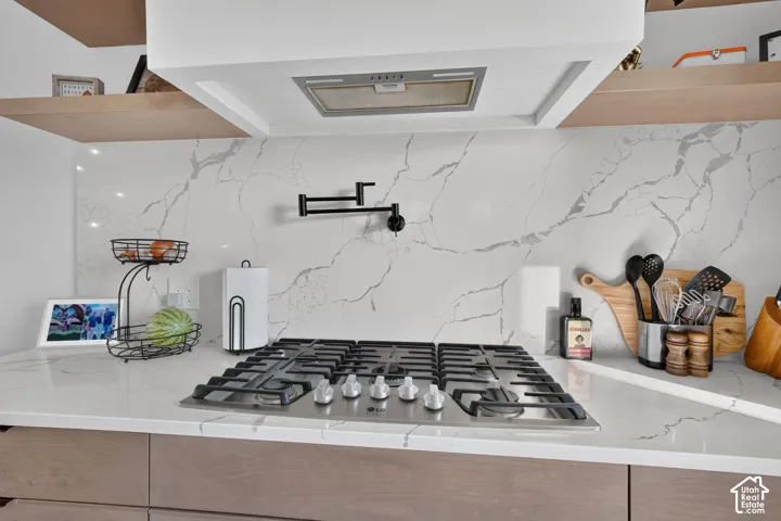 Integrated gas range with a stainless steel finish, mounted beneath a contemporary range hood