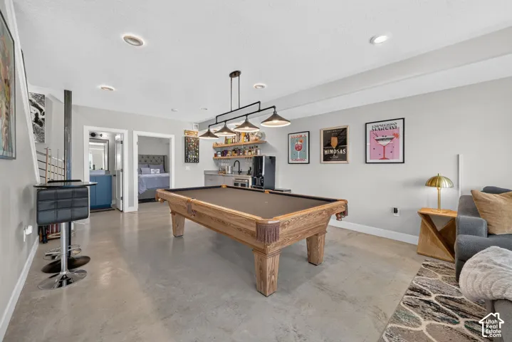 Polished concrete flooring, recessed lighting, built-in wet bar with shelving, modern track lighting, and a billiards table