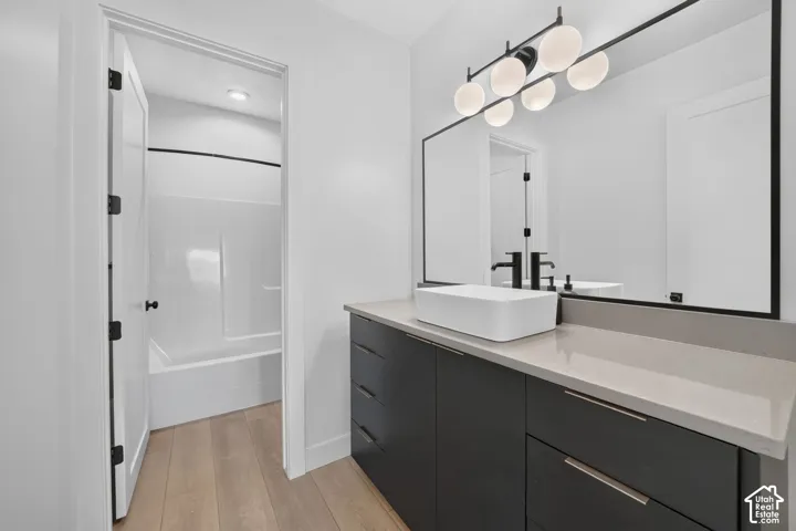 Modern vanity with a rectangular vessel sink, gray countertop, dark wood-finish cabinetry, and a large framed mirror