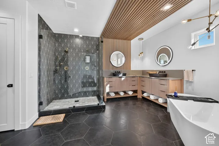Walk-in shower with geometric tile, glass enclosure, and gold-finish fixtures