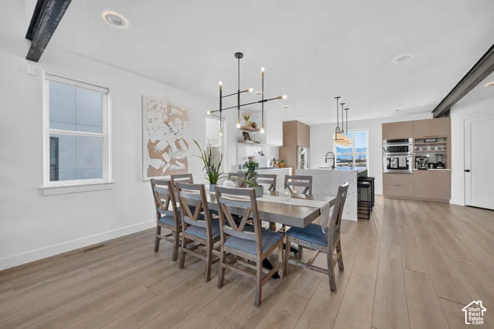 Open-concept living space with wood-finish flooring, recessed lighting, and a modern kitchen featuring a central island with an integrated sink and built-in appliances