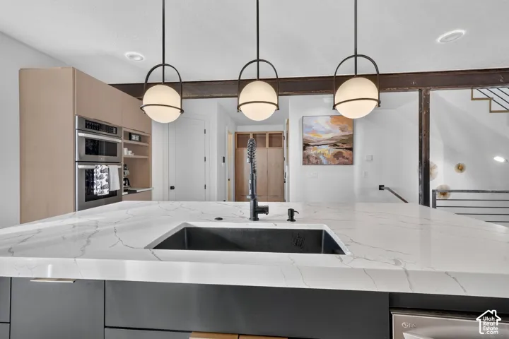Kitchen island with a white veined countertop, integrated black sink, and black pull-down faucet