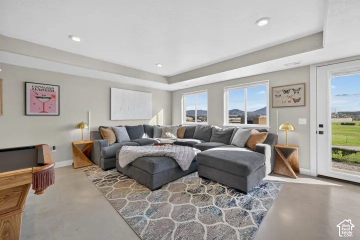 Recessed lighting illuminates this space featuring light gray walls, wood-finish flooring, multiple windows, and a glass-paneled exterior door