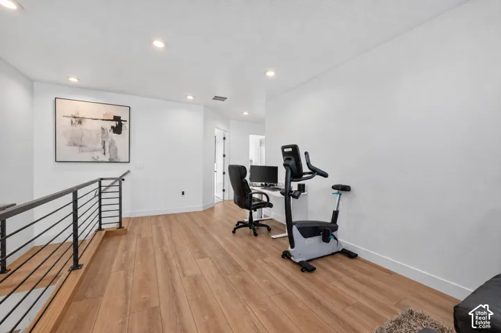 Upper-level landing featuring wood-finish flooring, recessed lighting, and a contemporary metal railing