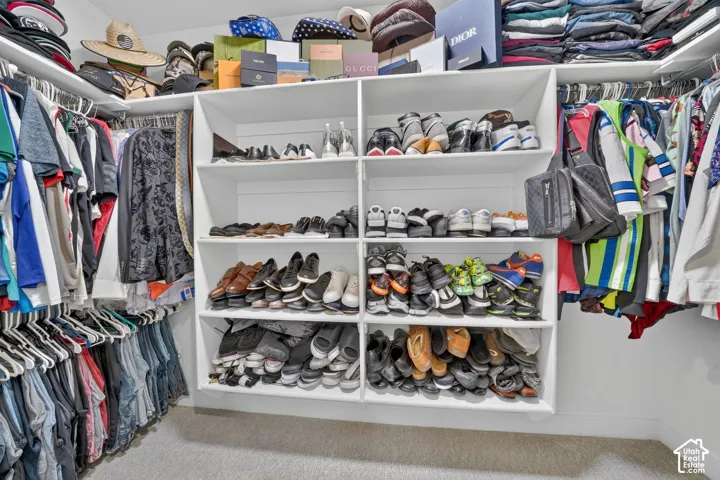 White built-in shelving, integrated shoe storage, multiple hanging rods, and light-toned carpet