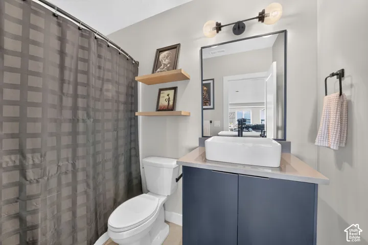 Modern vanity featuring a rectangular vessel sink, dark cabinetry, and light-toned countertop
