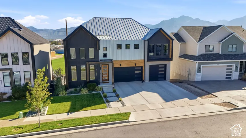 Modern exterior with a contrasting facade, metal roof, two-car garage, and landscaped front yard with stepping stones