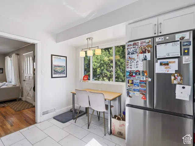 Kitchen area featuring white tile flooring, white cabinetry, and a stainless steel refrigerator