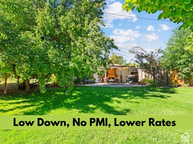 Expansive lawn with mature trees and a fenced perimeter, featuring a covered patio area
