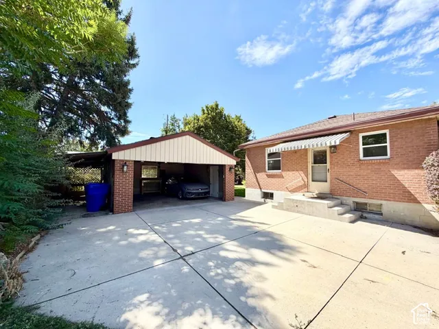 Brick exterior residence featuring a carport, an extended covered parking area, and a concrete patio
