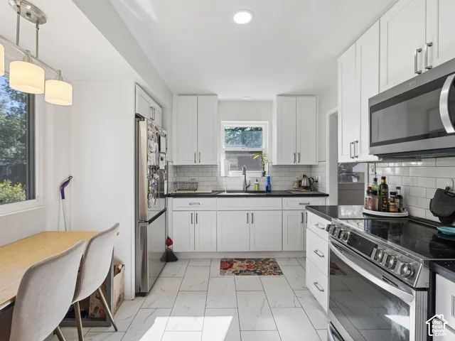 Kitchen with white shaker cabinetry, dark countertops, a subway tile backsplash, and stainless steel appliances
