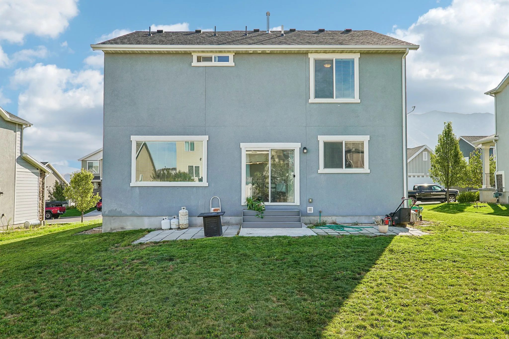 Blue stucco exterior with multiple windows, sliding glass door, and concrete patio