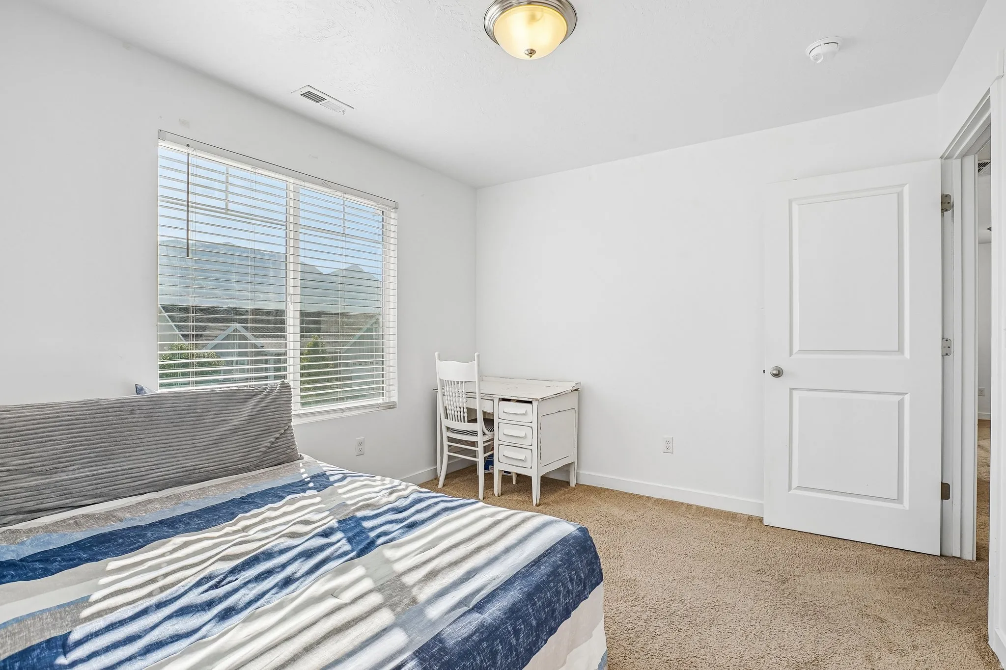 Carpet flooring, white walls, flush mount ceiling light, white door, and a large window with blinds