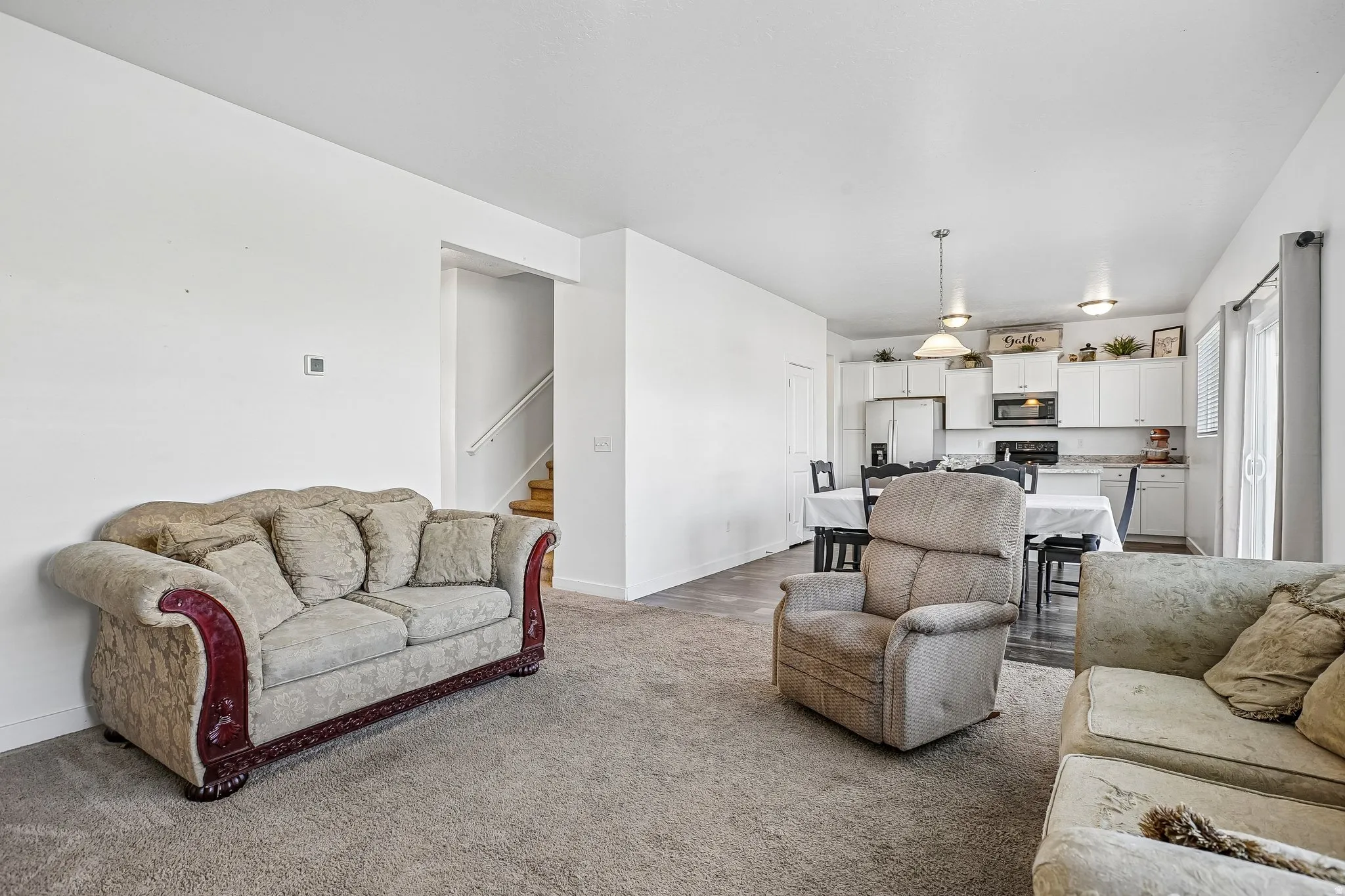 Open-concept living area with carpet flooring and white walls