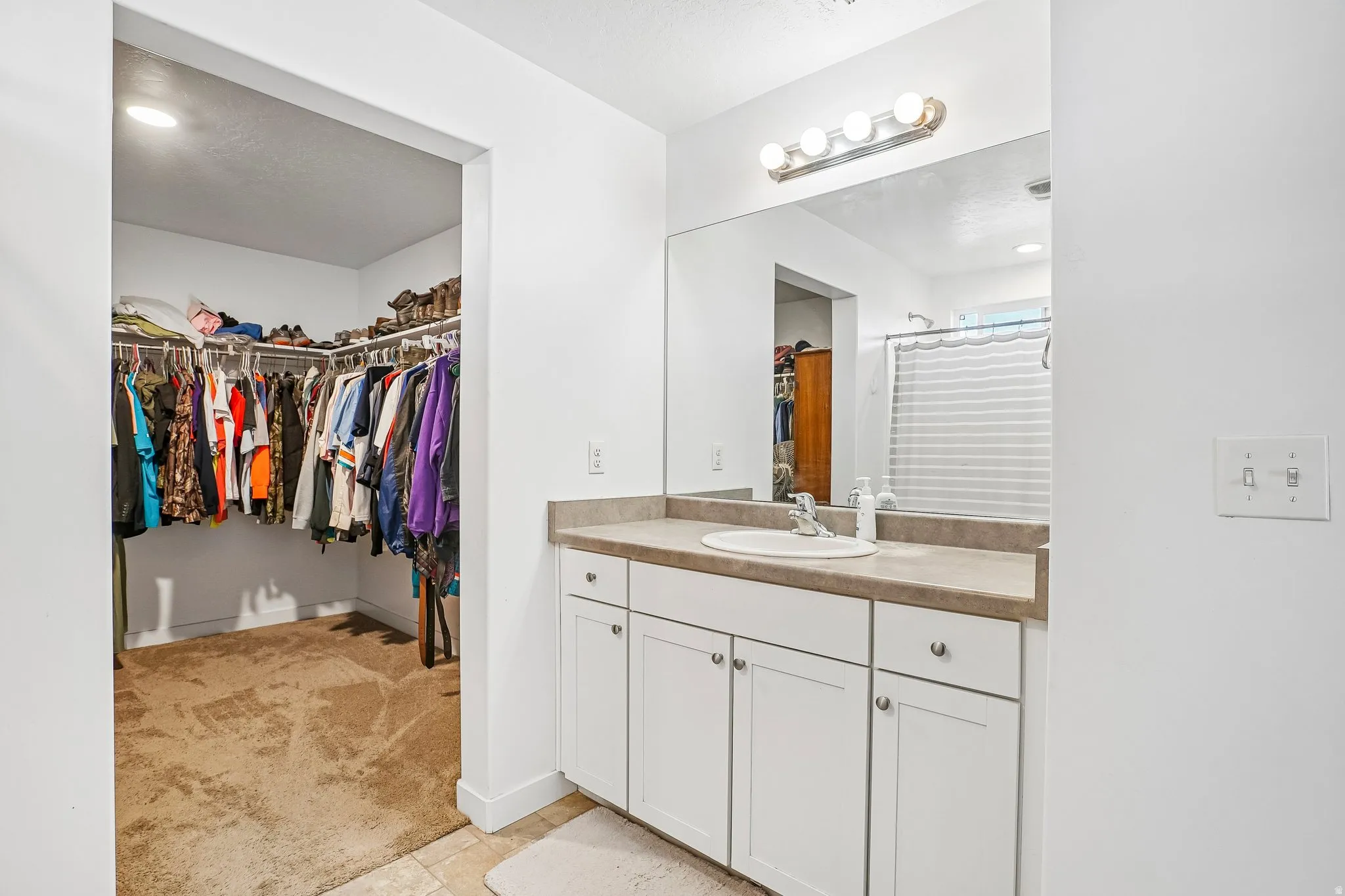 White vanity with a single basin sink and a neutral-toned countertop