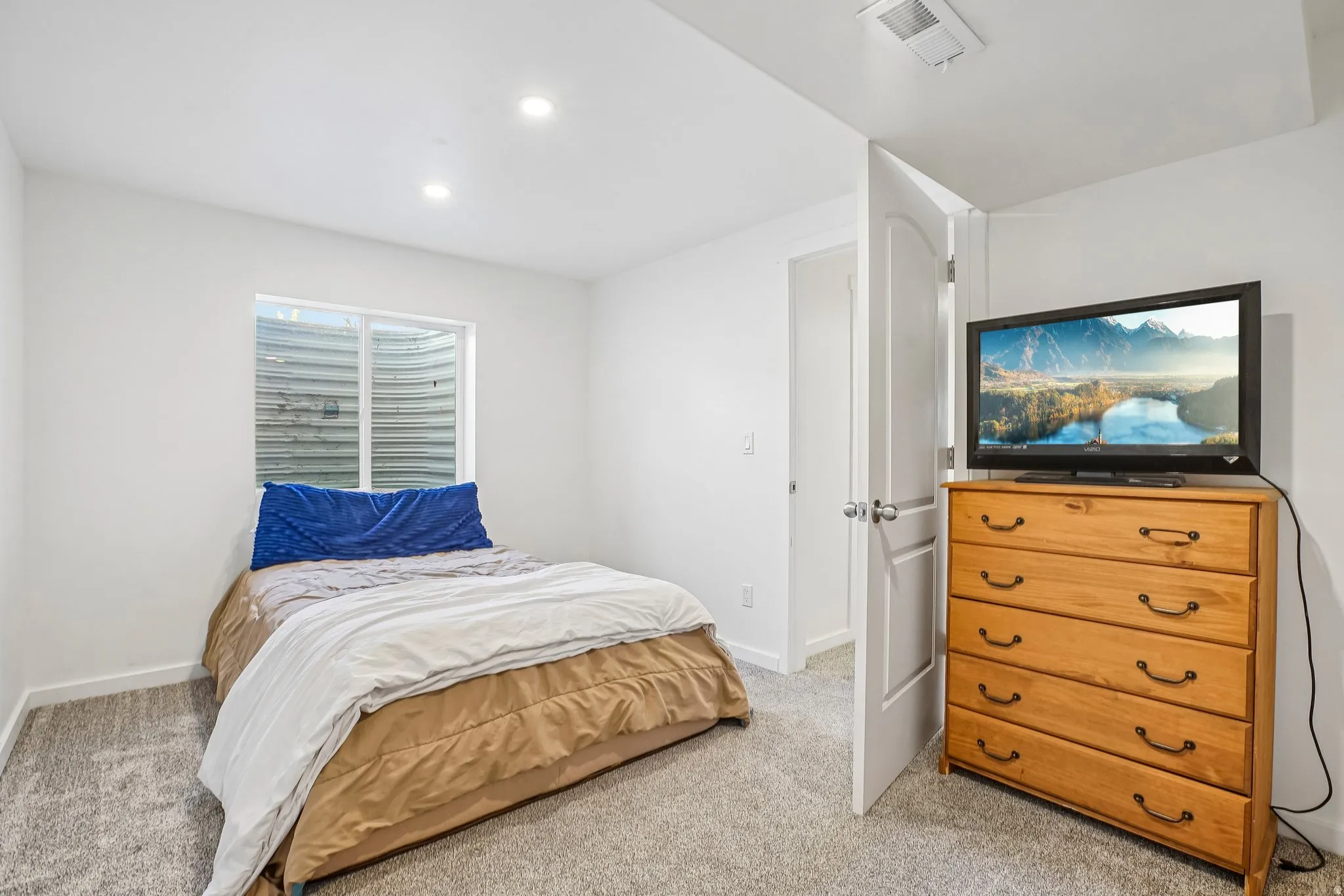 Recessed lighting, light gray carpeting, and a white interior door with a brushed nickel knob