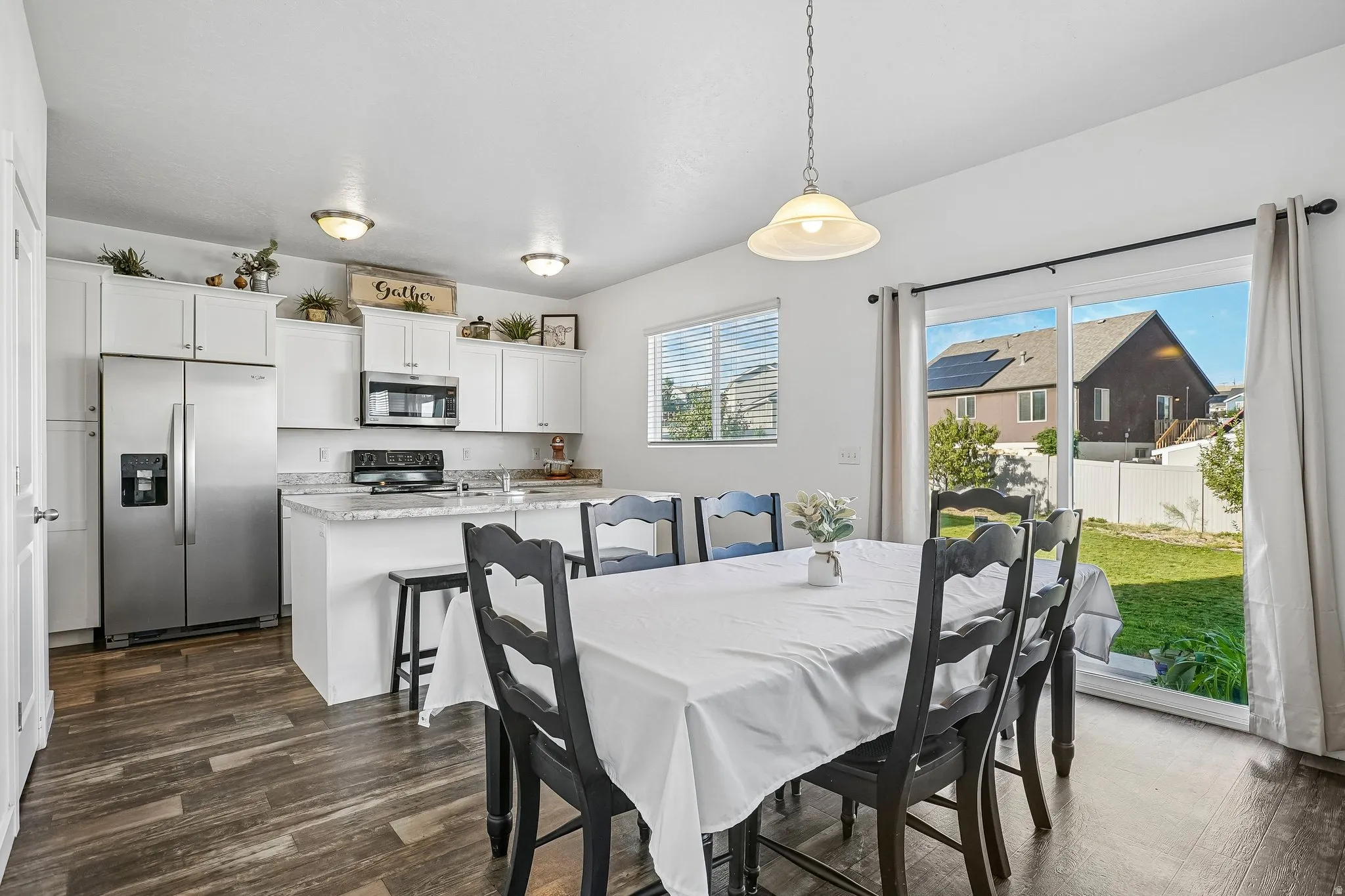 Kitchen featuring white cabinetry, stainless steel appliances, an island with countertop seating, and wood-finish flooring