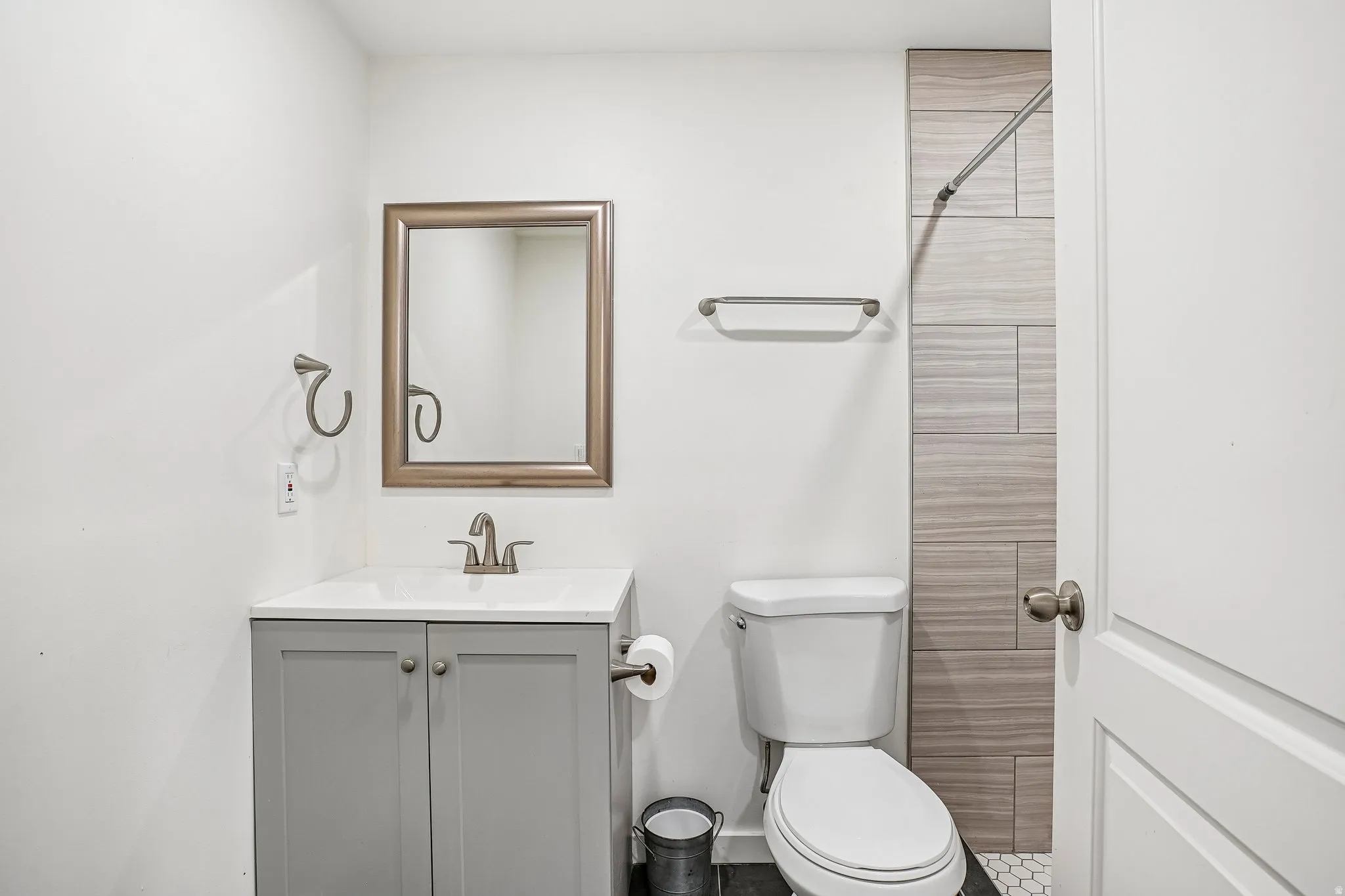 White vanity with gray shaker-style cabinetry, a polished chrome faucet, and a framed mirror