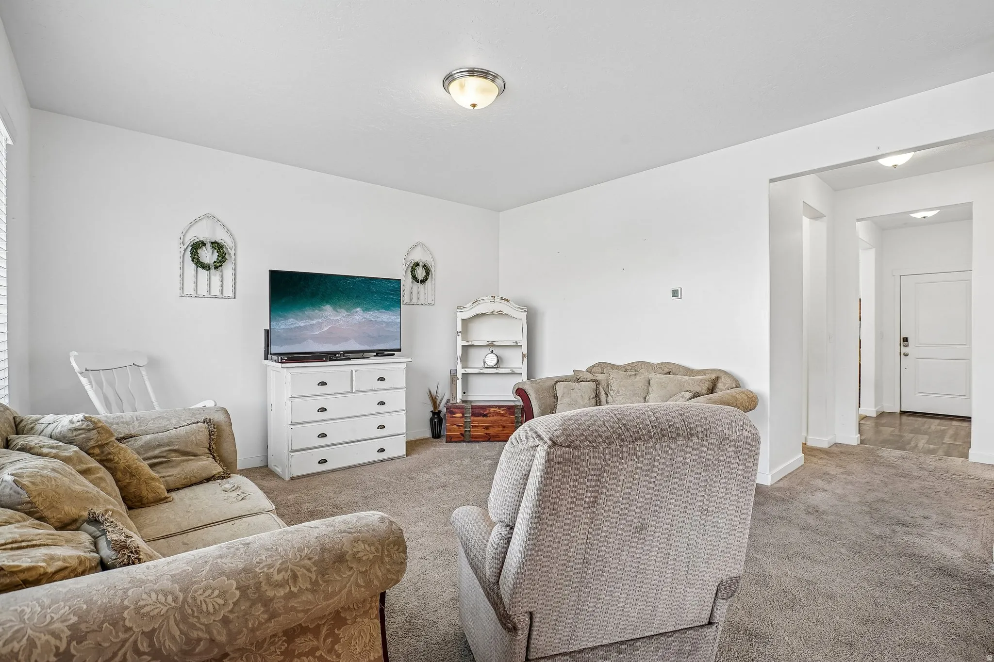Carpeted living area with white walls and a ceiling-mounted light fixture