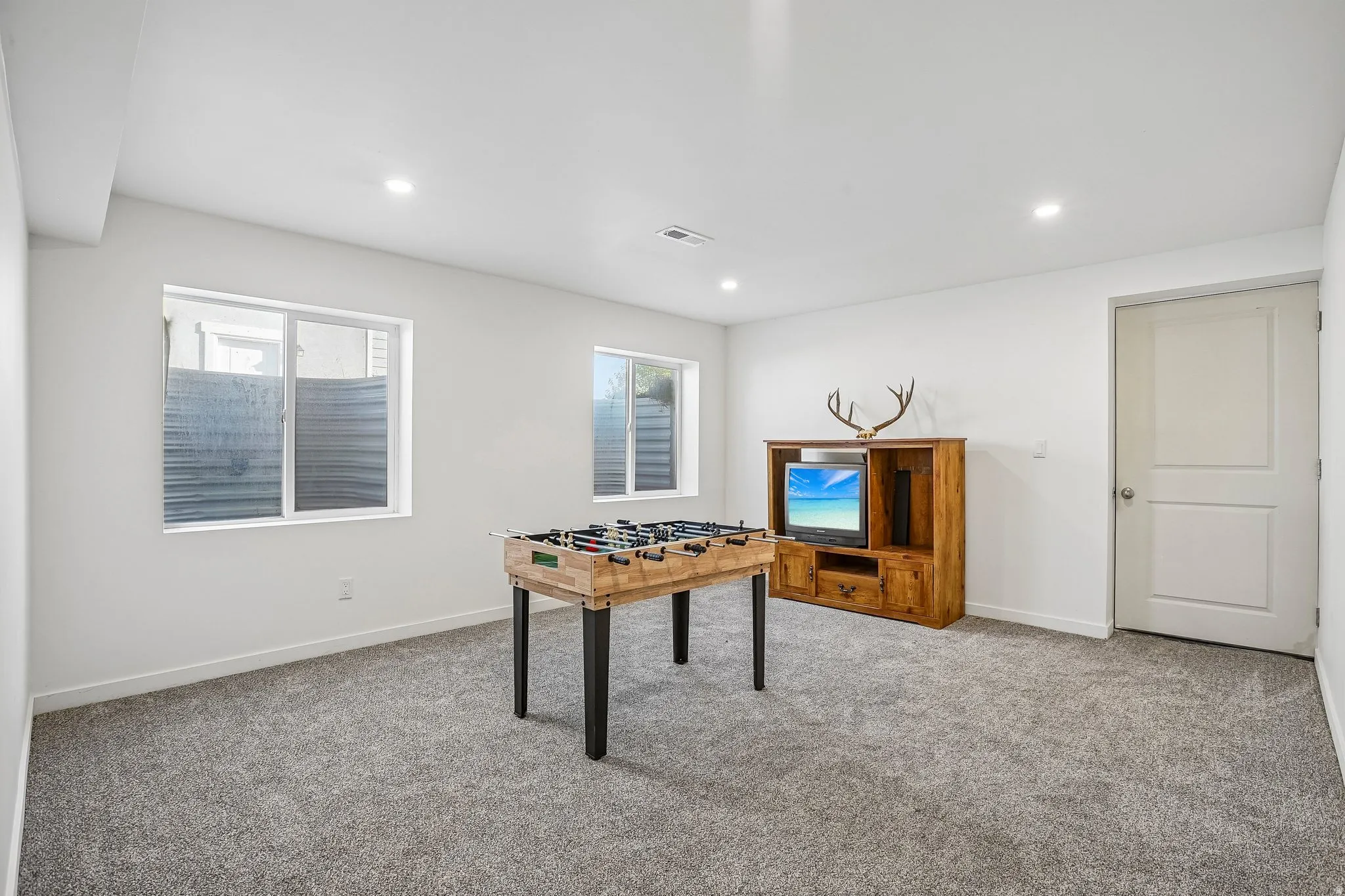Carpeted room with recessed lighting and two windows