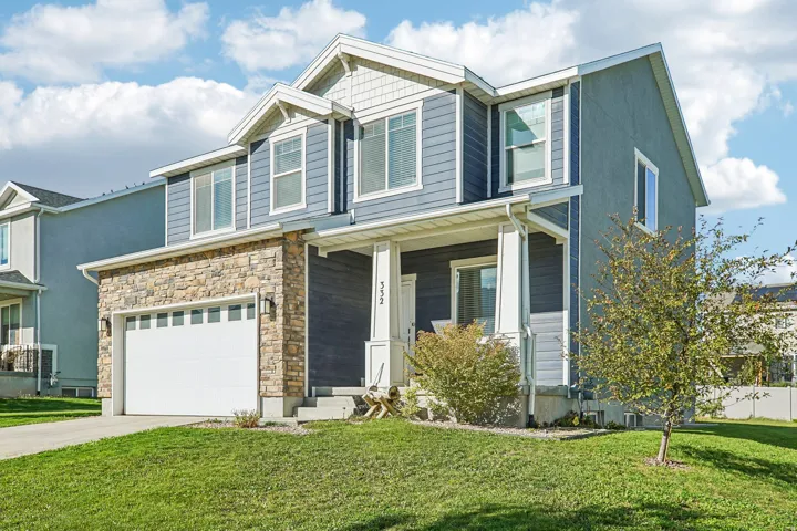 Two-story residence featuring a stone veneer garage with a white sectional door, blue siding, white trim, and a covered porch with white pillars