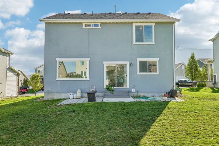 Blue stucco exterior with multiple windows, sliding glass door, and concrete patio