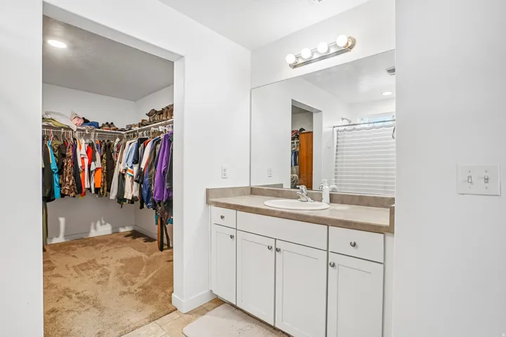 White vanity with a single basin sink and a neutral-toned countertop