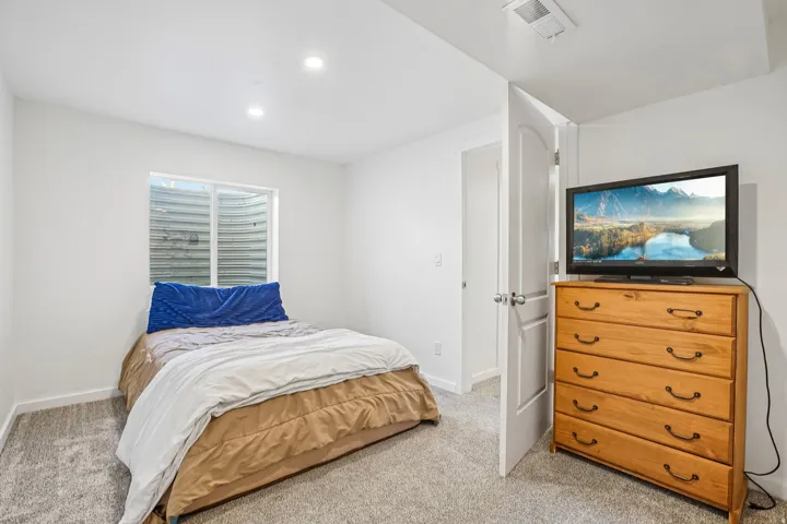 Recessed lighting, light gray carpeting, and a white interior door with a brushed nickel knob