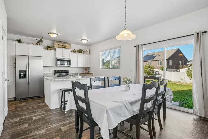 Kitchen featuring white cabinetry, stainless steel appliances, an island with countertop seating, and wood-finish flooring