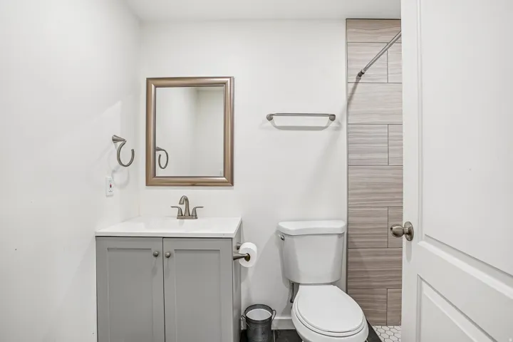 White vanity with gray shaker-style cabinetry, a polished chrome faucet, and a framed mirror