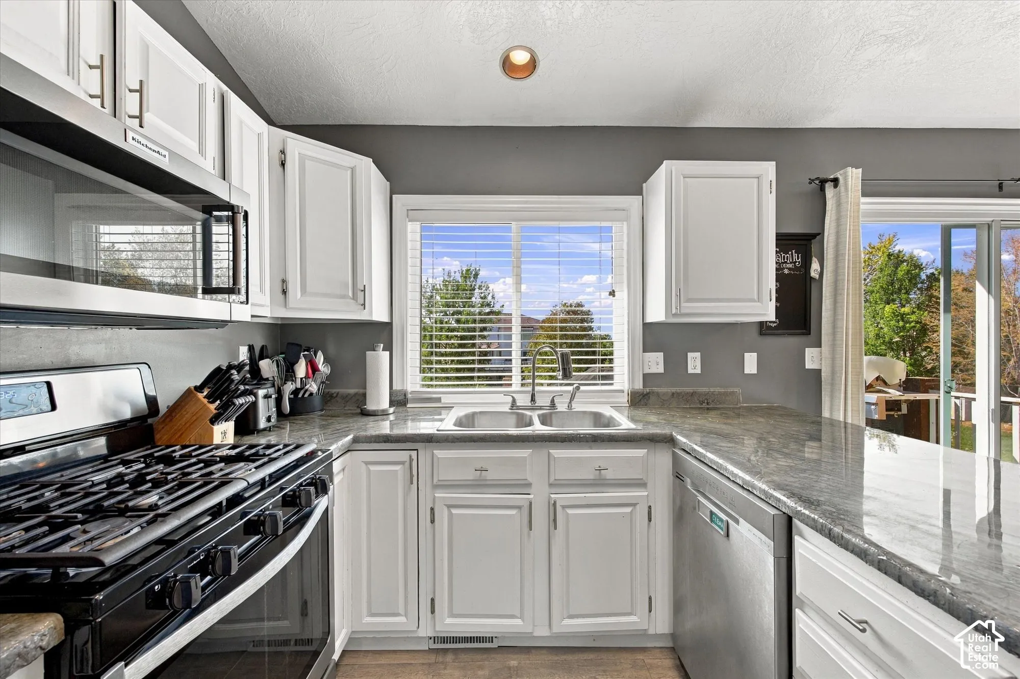Stainless steel appliances, white cabinetry, a double basin sink, and ample countertop space