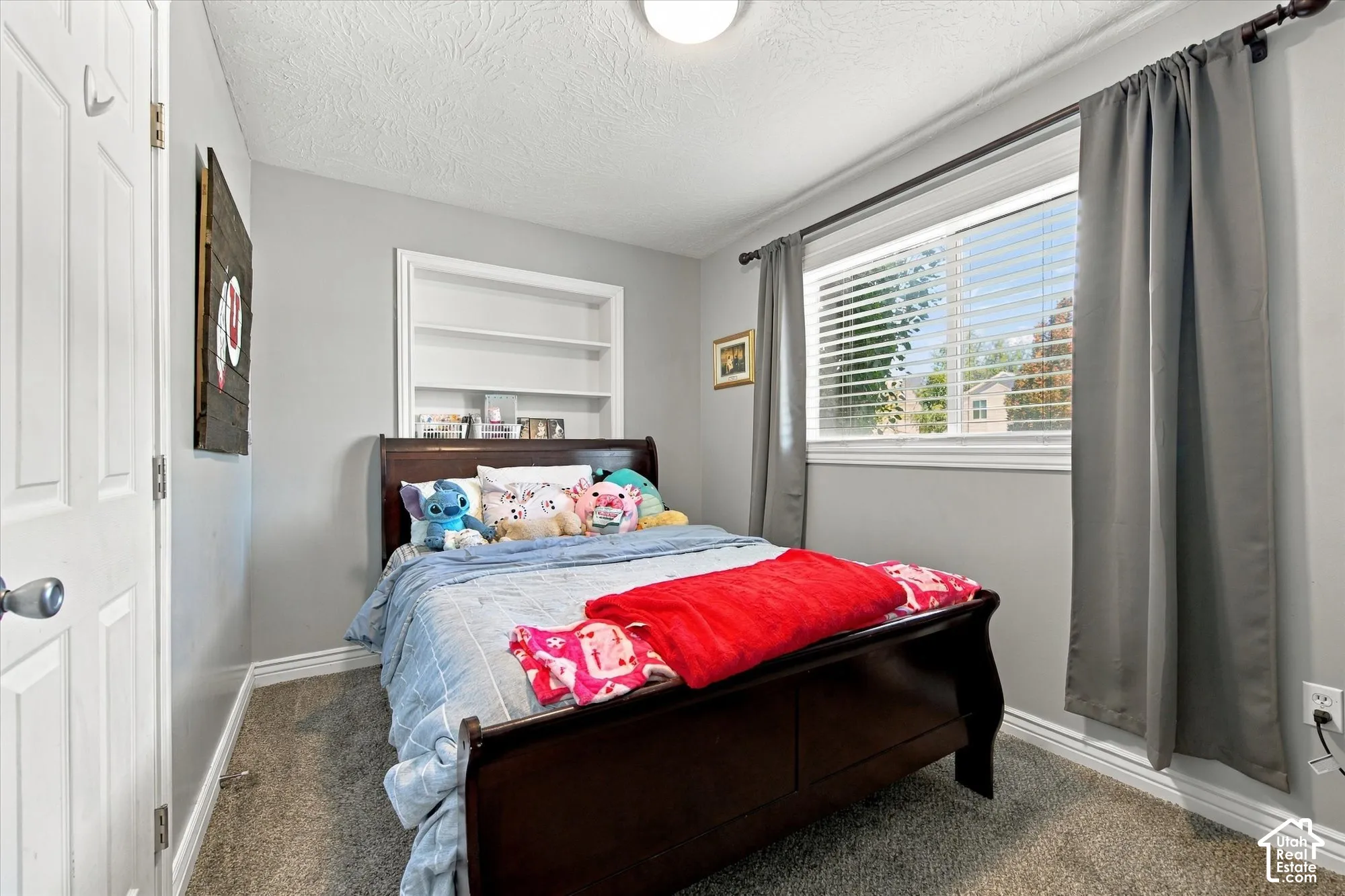 Built-in shelving, flush-mount ceiling light, window with blinds, and paneled interior door