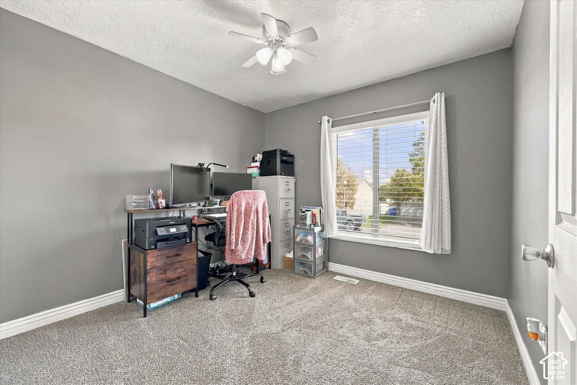 Carpeted flooring with a white trim, featuring a ceiling fan and a window with white blinds