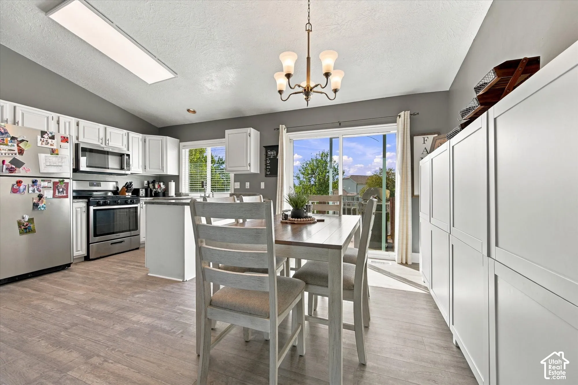 Kitchen featuring wood-finish flooring, white cabinetry, stainless steel appliances, and a sliding glass door