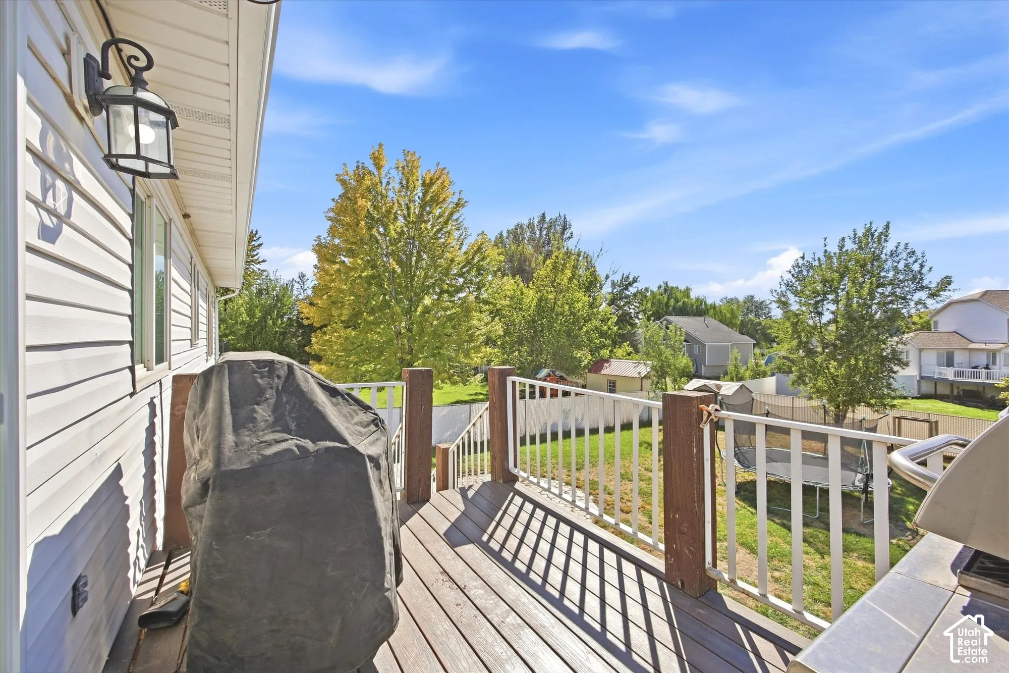 Expansive outdoor deck with wood-finish flooring, white railing, and exterior wall lighting