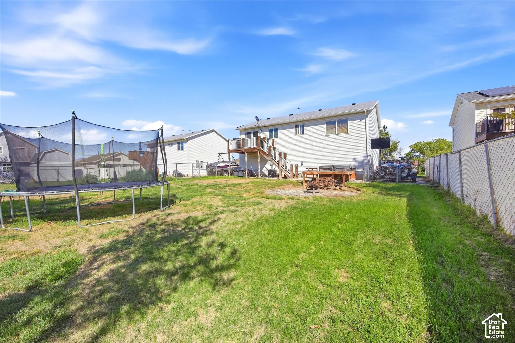 Expansive backyard with a manicured lawn, a chain-link fence, and a multi-level deck