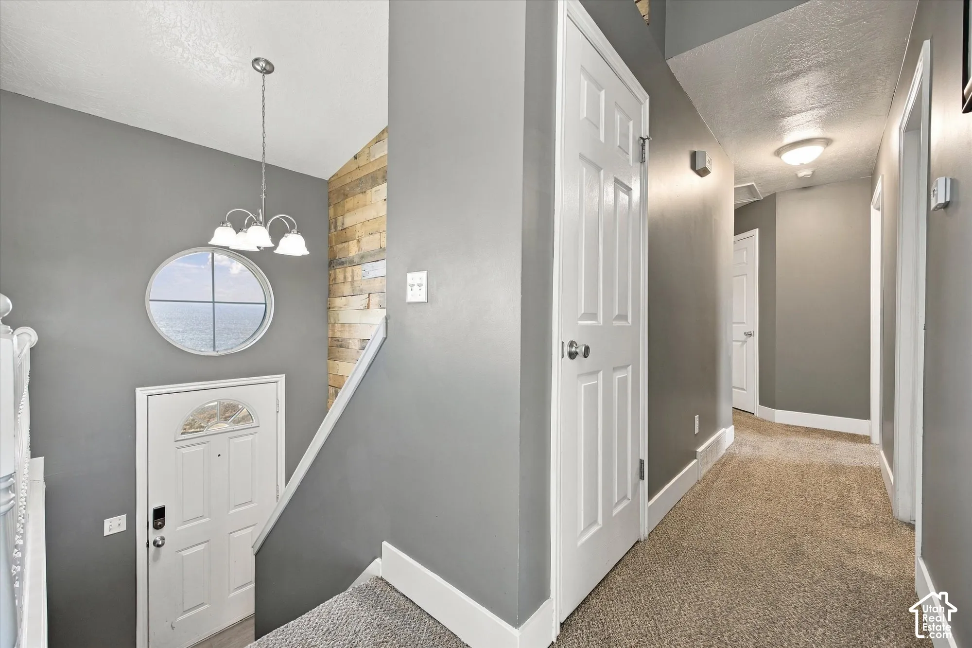 Entryway featuring a decorative round window, a three-light chandelier, and a wood-paneled accent wall