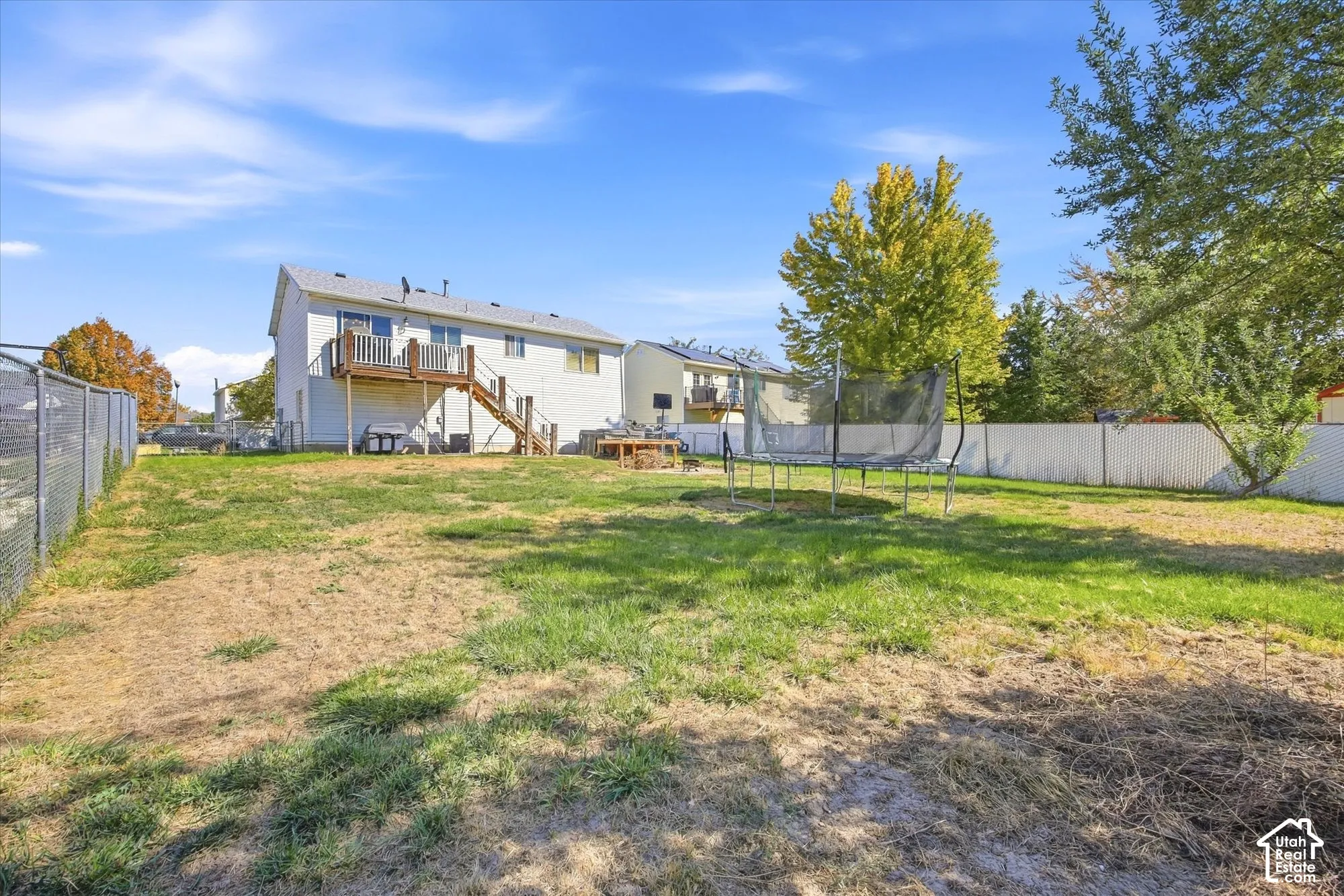 Expansive backyard with a chain-link fence, white privacy fence, and mature trees