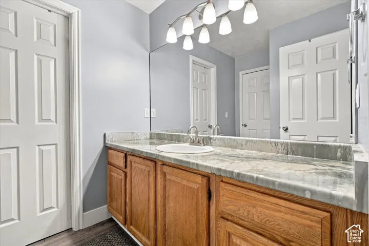 Vanity with a built-in sink, wood cabinetry, and a stone countertop
