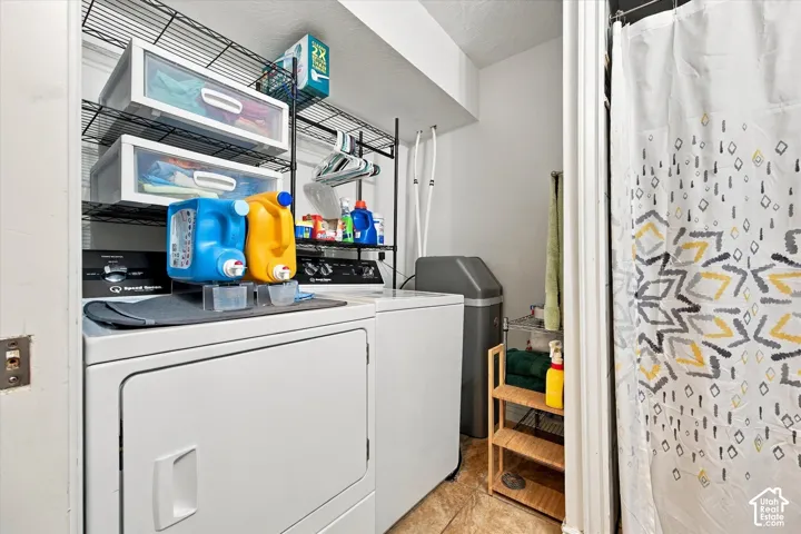 Laundry area featuring stacked appliances, overhead wire shelving, and a tiled floor