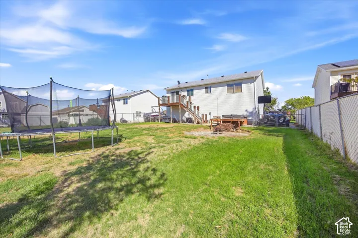 Expansive backyard with a manicured lawn, a chain-link fence, and a multi-level deck