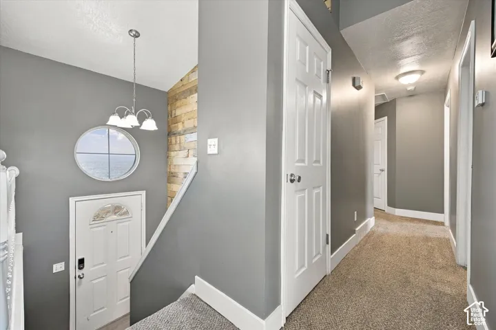 Entryway featuring a decorative round window, a three-light chandelier, and a wood-paneled accent wall
