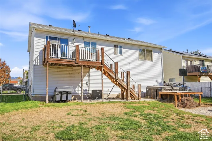 Exterior featuring white siding, a raised wood deck with railing, and a wood staircase