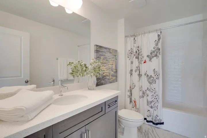 Bathroom featuring a vanity with an integrated sink, a large mirror, a chrome faucet, and a shower-tub combination with subway tile surround